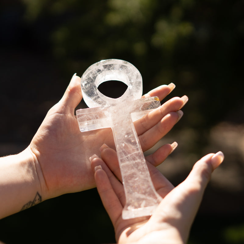 Hands holding a crystal key against a blurred natural background