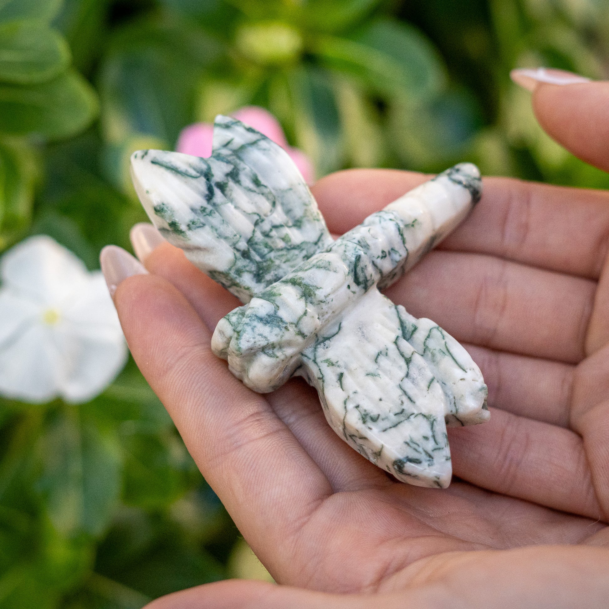 Hand holding a stone butterfly with a natural background