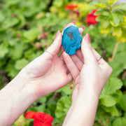 Hands holding a blue chrysocolla crystal slice in a natural and serene setting to enhance spirit and energy
