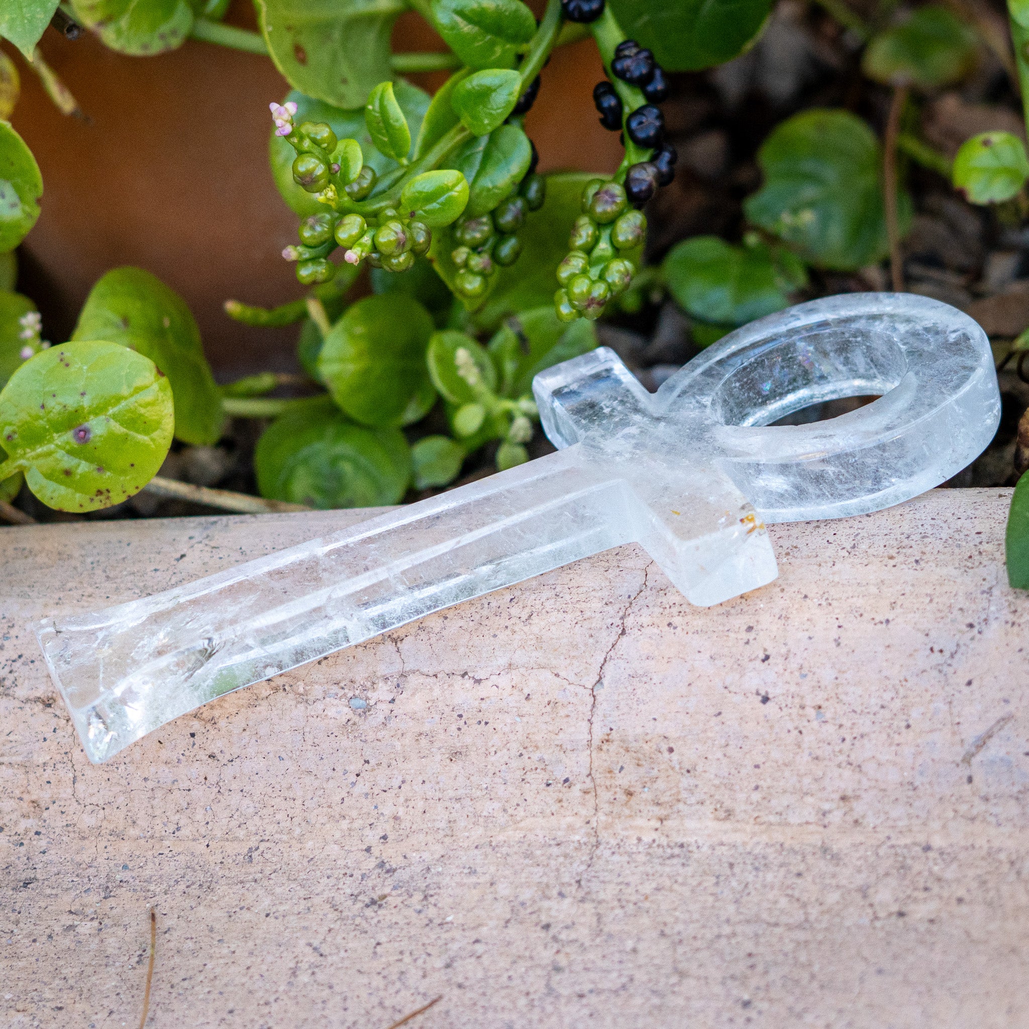 Quartz Crystal healing tool on a stone surface with green plants in the background