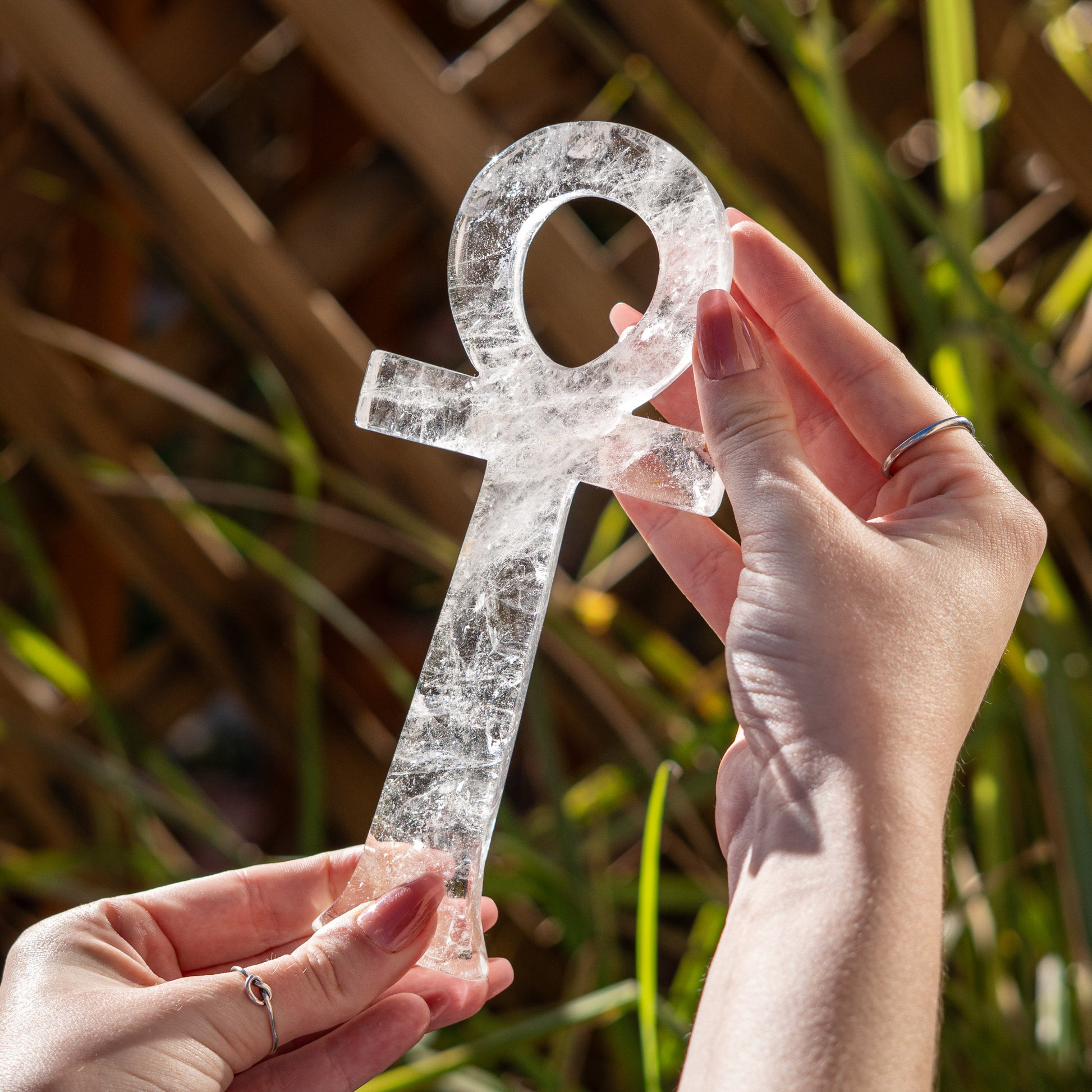 Clear crystal Ankh symbol held by a hand against a natural background